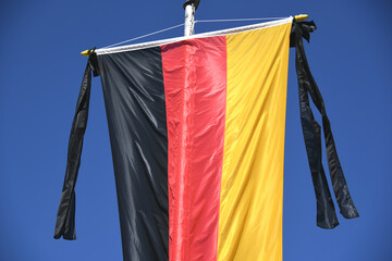 Die Nationalflagge der Bundesrepublik Deutschland schwarz rot gold hängt am Fahnenmast Als Symbol der Staatstrauer ist der Trauerflor mit zwei schwarzen Schleifen an der Fahne angehängt Volkstrauertag