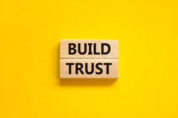 Build trust symbol. Concept words Build trust on wooden blocks on a beautiful yellow table yellow background. Business and build trust concept, copy space.