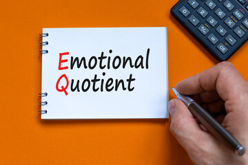 EQ emotional quotient symbol. Concept words EQ emotional quotient on white note. Businessman hand, calculator. Beautiful orange background. Business EQ emotional quotient concept, copy space.