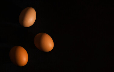 Minimalism. Fresh brown eggs with hard shadows on a dark background. Natural home product. Top view. Copy space.
