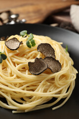 Tasty spaghetti with truffle on black plate, closeup