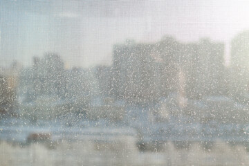 Snow flakes in winter on the mosquito net on the balcony. Behind the grid is a sunny, clear day in the city.