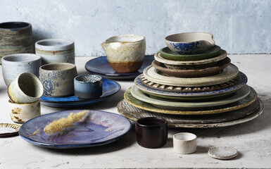 A variety of plates, glasses and saucers handmade from clay. Close-up, glazed dishes..