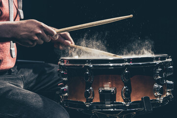 The drummer's hands hold drumsticks and play the snare drum.