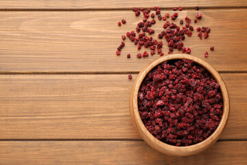 Dried red currants and bowl on wooden table, flat lay. Space for text
