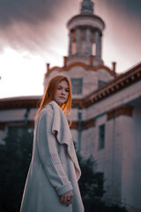 a girl stands in the autumn against the backdrop of a building