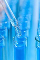 Dripping reagent into test tube with blue liquid, closeup. Laboratory analysis