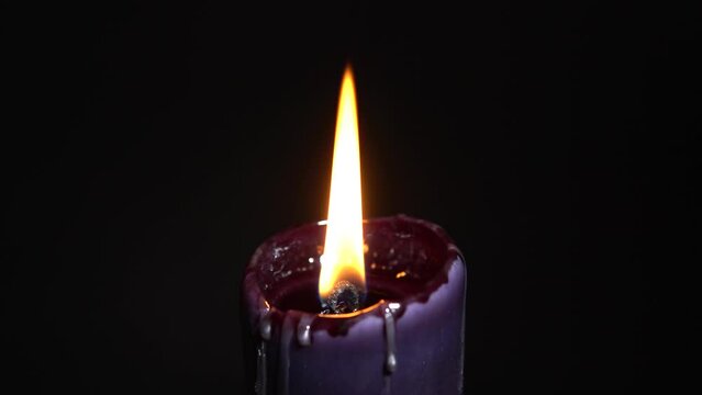 Black magic candle with dark background, selective focus. Magical Halloween horror concept. Bee wax candle burning very quick. Macabre and darkness mood set up.