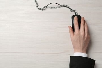 Top view of man using computer mouse at white wooden table, cable with chain. Internet addiction