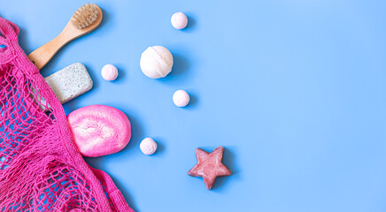 Spa composition with bath accessories in a pink string bag, flat lay.