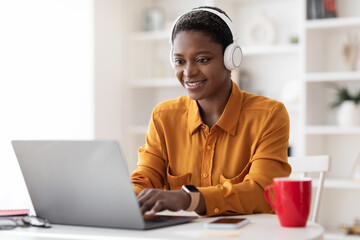 Attractive black woman attending webinar, using laptop and headset
