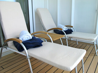 Sun loungers and deck chairs on teak deck terrace or patio or sun pool deck of luxury cruiseship...