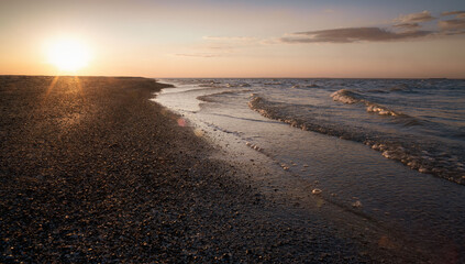 Sunset on the shore of the sea of ​​Azov and cascades of waves.