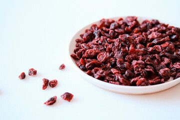 Dried cranberries on a white plate on a light background. Copy space.
