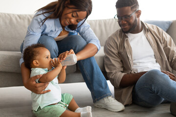 Young African American parents feeding child from bottle