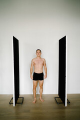 Young Caucasian man in underwear stand at home.