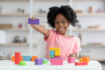 Cute little black girl showing purple wooden block