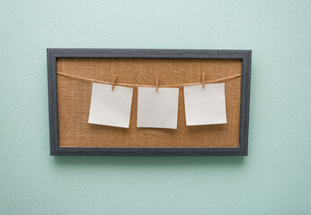 white sheets of paper hanging isolated on a beige board on clothespins free space mockup