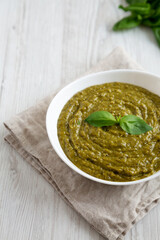 Homemade Green Pesto in a White Bowl, side view. Space for text.