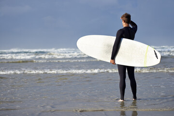 Fototapeta na wymiar Ready to take on the waves. Shot of a young man about to go surfing.