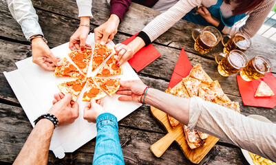Friends room mates sharing pizza at home garden party - Food life style concept with young people having fun together eating takeaway meal at outdoor pizzeria - Tilted composition with warm filter