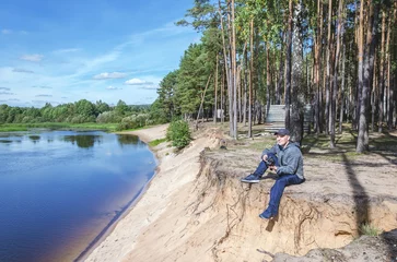 Gordijnen Photographer relaxes in nature near the river. © alexey351