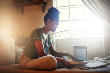 The latest study material is available online. Full length shot of a young female student studying at home.