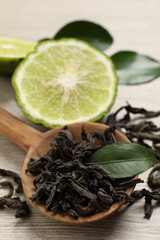 Dry bergamot tea leaves and fresh fruit on light wooden table, closeup