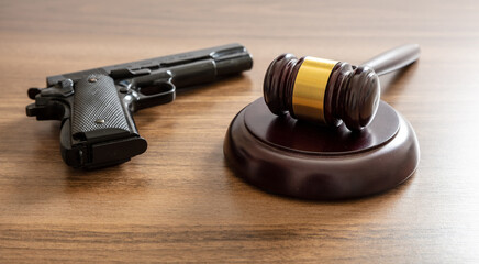 Crime, gun carry and use punishment concept. Judge gavel and handgun on table, close up