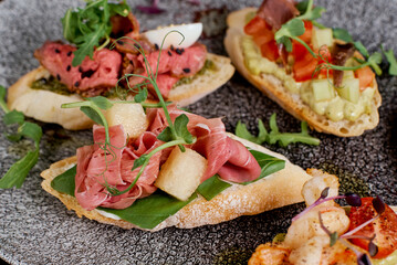 Oval brusquettes with different fillings on a gray oval plate