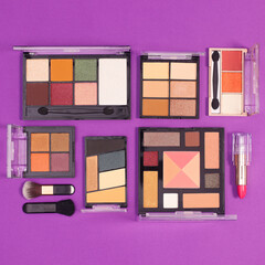 Creative layout with make up shadows brushes and lipsticks on purple background. Flat lay minimal cosmetics frashion products