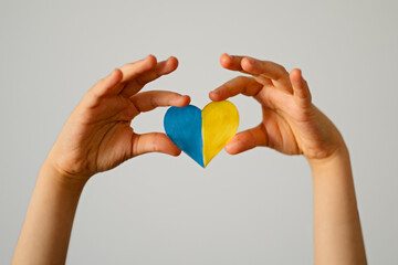 A heart-shaped badge depicting the State Flag of Ukraine as a symbol of patriotism and pride in one's country. State symbol of Ukraine in children's hands