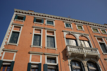 Detail of a beautiful Venetian palace with ocher walls and windows and balconies with white details.