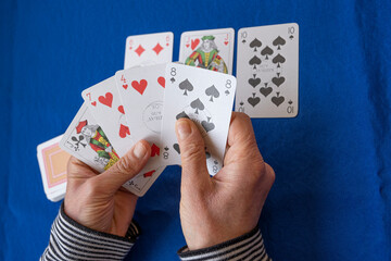 Close up hands of woman playing cards on blue table.Old woman playing cards in home.