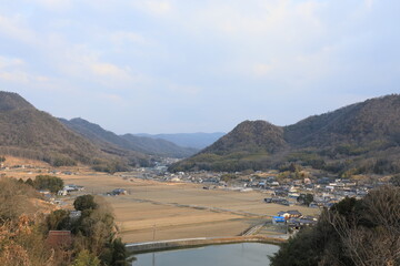 高台から見下ろす田んぼと山々が広がる田舎の風景