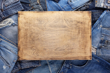 Stack of blue jeans denim and wood name plate. Jeans heap at wooden background texture