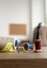 Thread spool and needle with sewing tools on table. Concept of clothes atelier