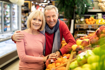 Attractive elderly couple posing at supermarket, copy space