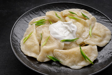 Boiled Ukrainian dumplings on a dark background, with space for text