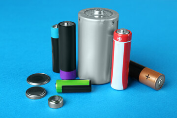 Different types of batteries on light blue background