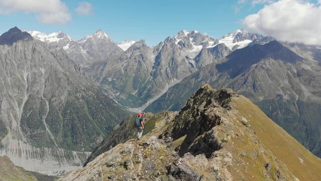 Woman with backpack hiking on mountain ridge in Caucasus mountains, Georgia