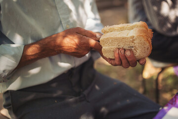 Hands of elderly man with slice cut  bread as a symbol of hard work and agriculture. Bread and...