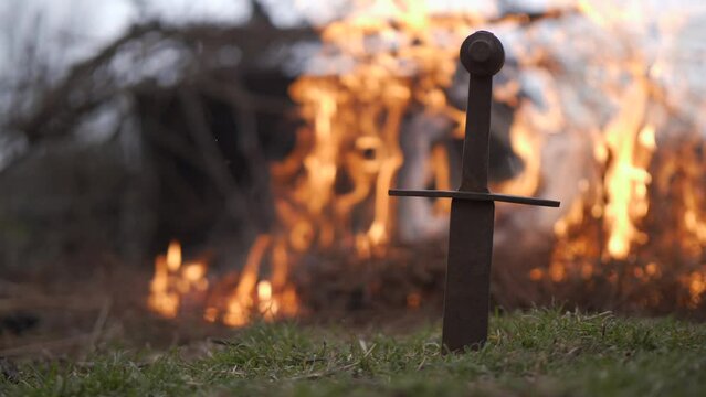the sword is stuck in the ground in the background fire