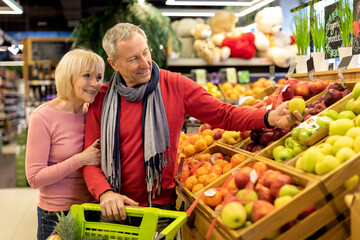 Loving elderly couple making shopping at supermarket