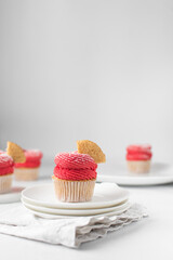 Red buttercream swirl on vanilla cupcake, plain cupcake decorated with american buttercream, cupcake on a plate