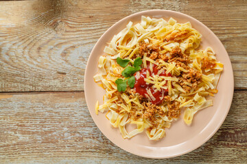 Pasta bolognese garnished with herbs and cheese in a plate on a wooden table. save a place.