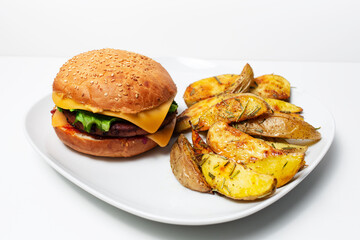 Studio photo of homemade vegan cheeseburger and roasted potatoes with rosemary.
