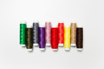Close-up top view of colourful thread spools isolated on white background.