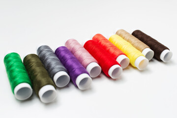 Close-up of colourful thread spools on white table.