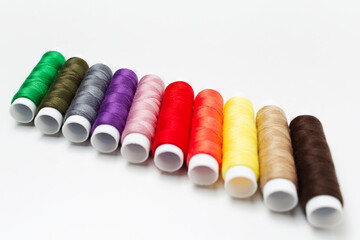 Close-up of colourful thread spools on white background. Plastic bobbins.